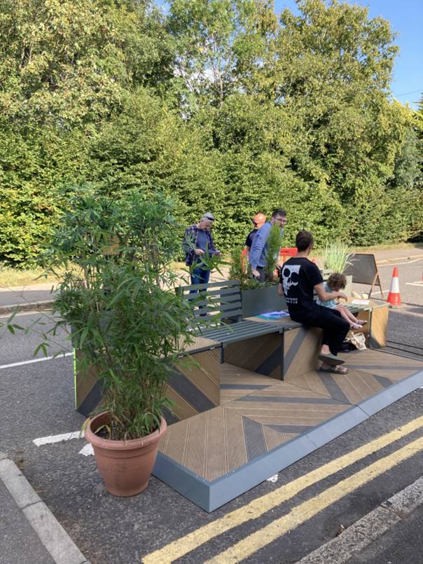 People sit on a pedlet surrounded by plants