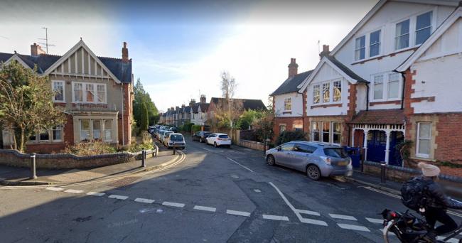 Cyclist crossing a junction with a residential street in the Divinity Road area surrounded by houses and parked cars