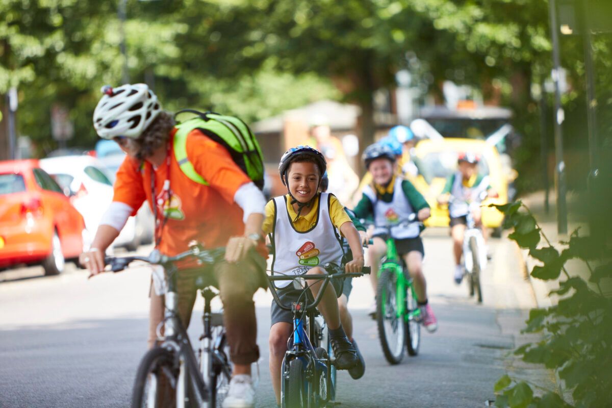 Children cycling along a road behind an instructor at a Bikeability cycle skills session 