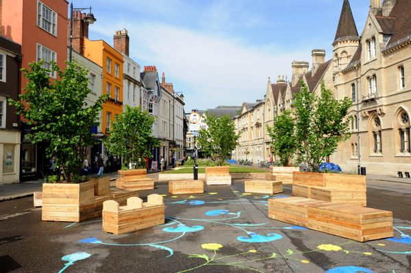 Area of Broad Street, Oxford, given over to seating, green planters and trees, surrounded by buildings