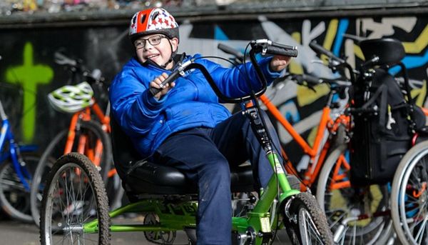 A child rides an adapted cycle